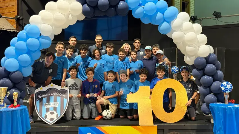 Teen players and coaches posing with the crest and the number 10