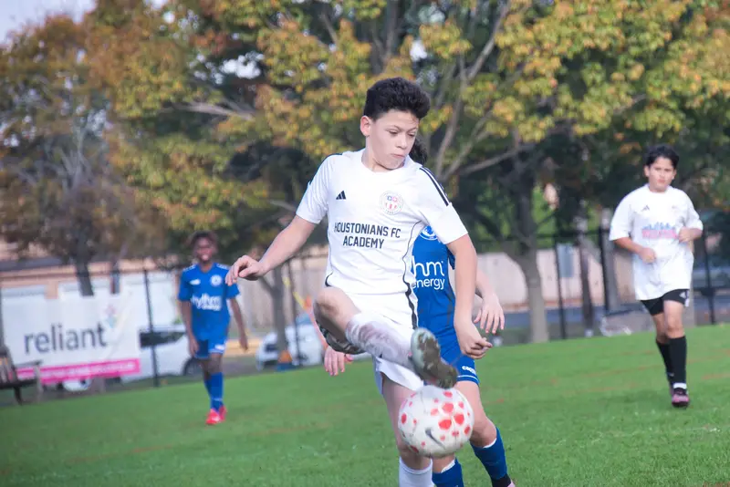 A Juniors player controls the ball under pressure during a match