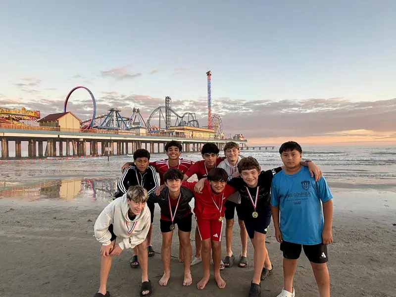 Players with medals on the beach at sunset in front of a pier
